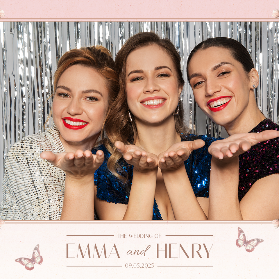 Three women blowing kisses in a wedding-themed photo booth frame.