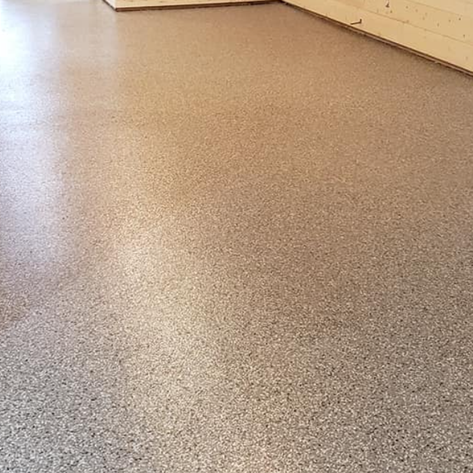 Seamless flake epoxy floor coating installed in a finished basement with wood accent walls.