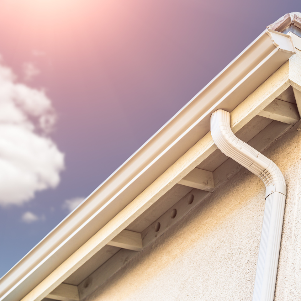 Residential home with a clean gutter and downspout system installed along the roofline.