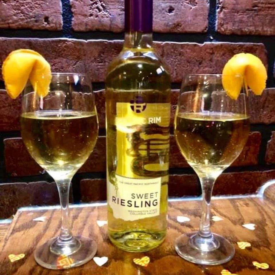Two glasses of white wine and a bottle displayed on a table inside Little Hunan restaurant.