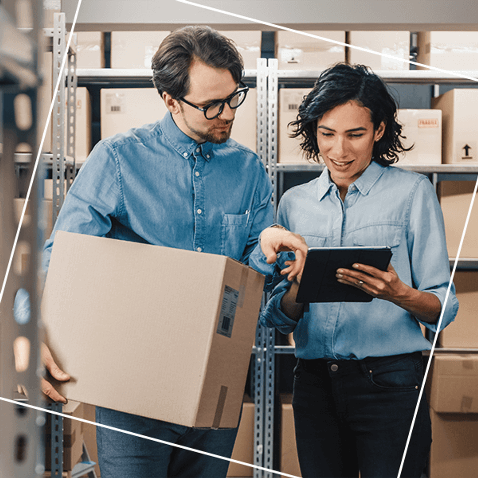 Man and women reviewing tablet in warehouse