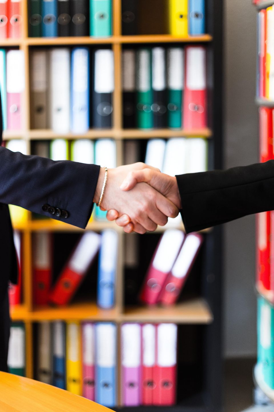 Two person handshakes in front of books on shelf 2058146