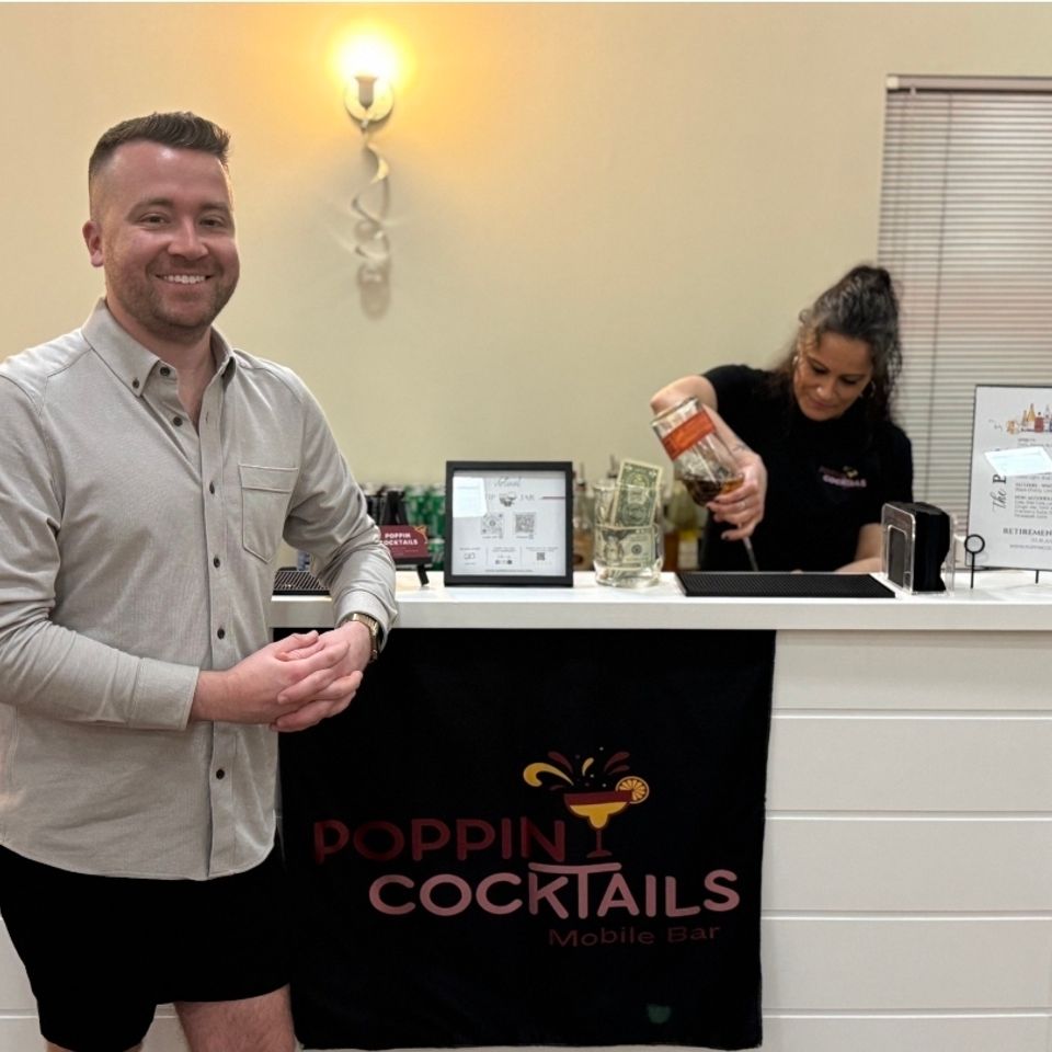Bartender pouring a drink while a guest stands at the bar during an event