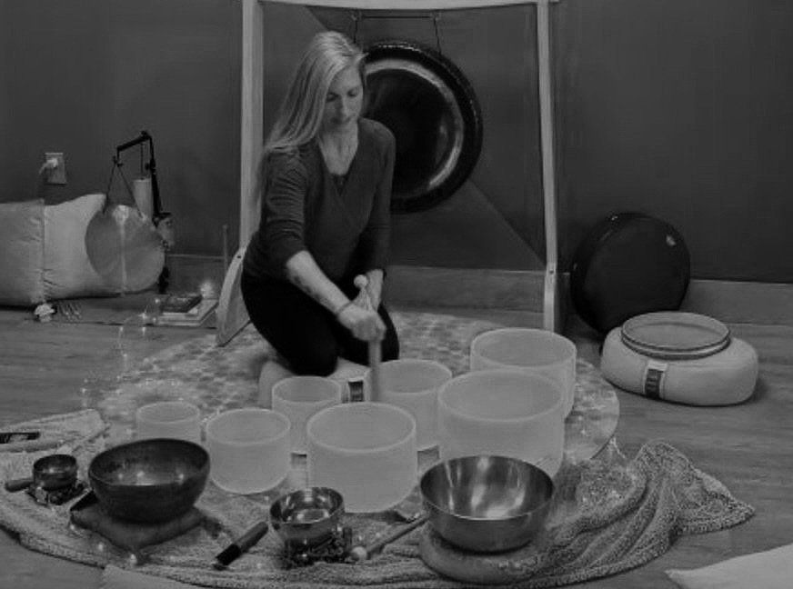 A person playing the sound bowls in black and white 