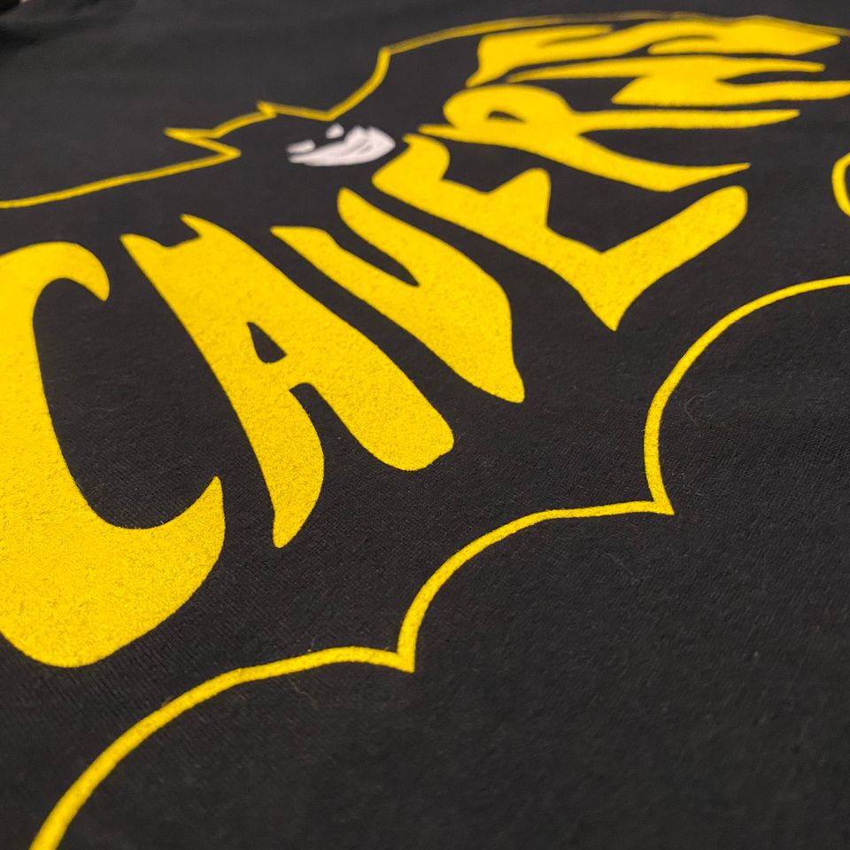 Batman logo with the word Caverns in yellow in the bat signal