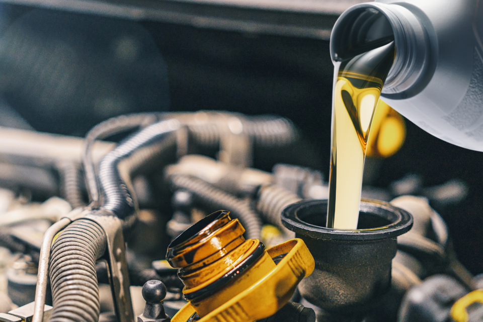 oil being poured into a vehicle engine during a professional oil change service.