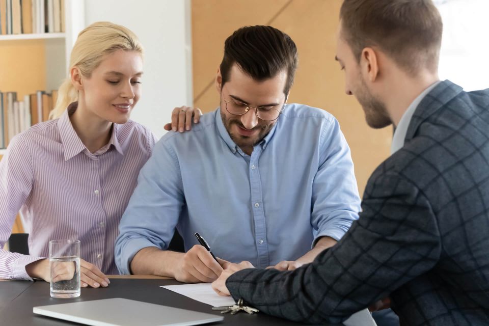 Couple signing document with insurance agent