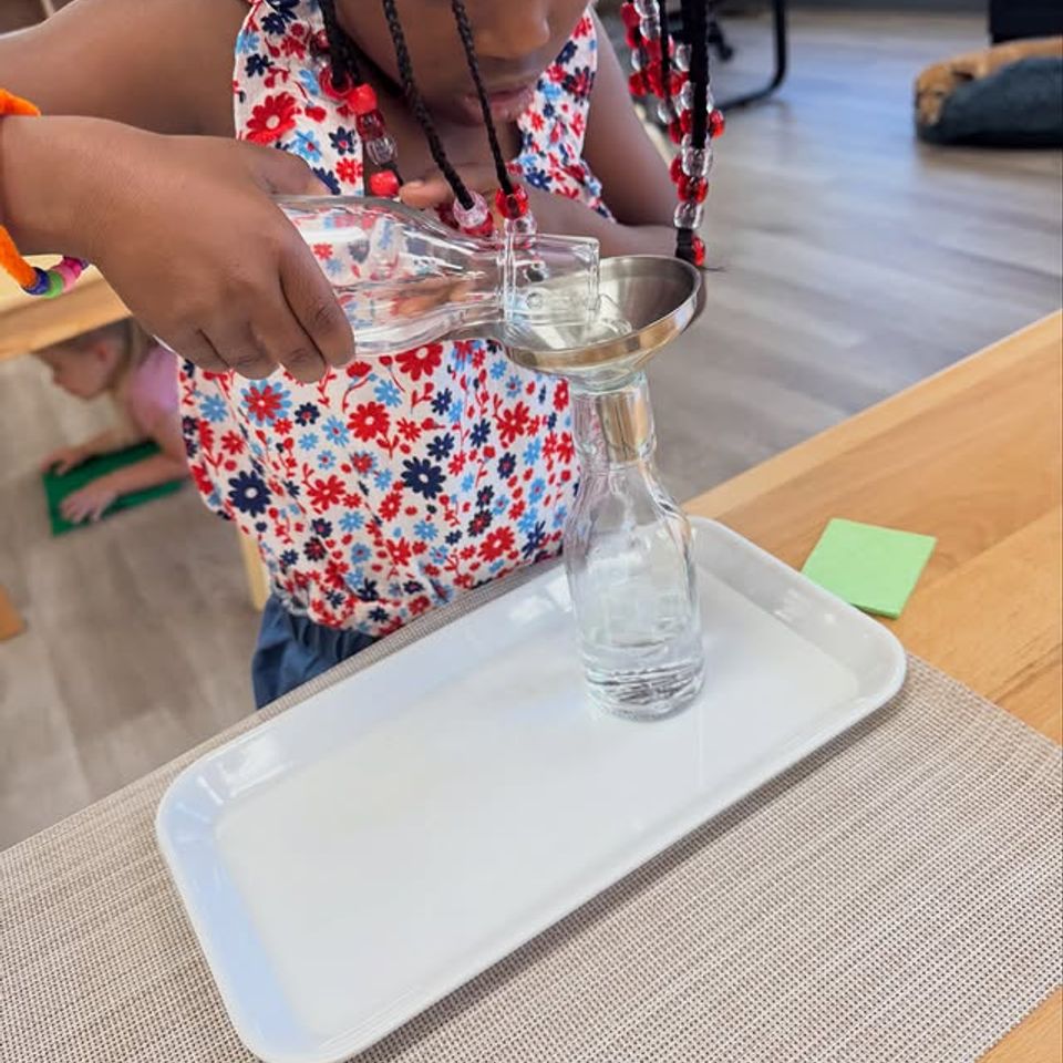 Child pouring water through a funnel into a bottle during Montessori practical life work in Palmdale CA