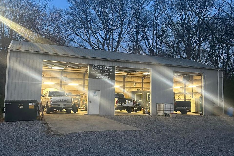 Stanley's Diesel Repair shop exterior with open service bay doors at dusk in Arab Alabama