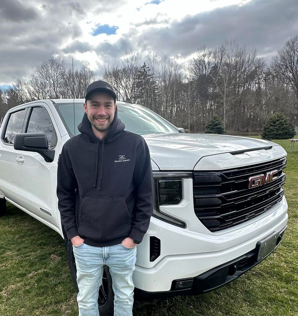 Dylan, owner of Elevation Exteriors, standing in front of a white GMC truck