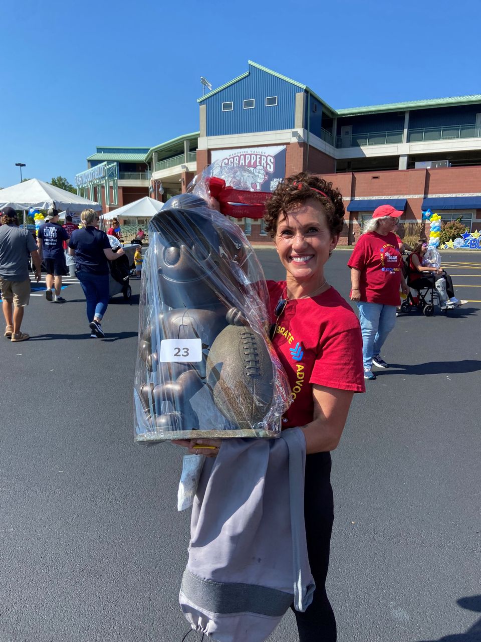 Buddy Walk attendee smiling while holding a wrapped raffle prize outside the DSAV Buddy Walk event venue.