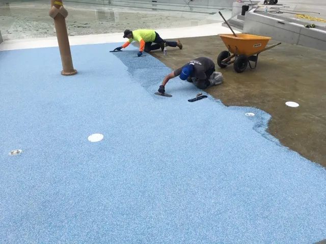 Preparing a pool deck surface before applying a decorative coating.