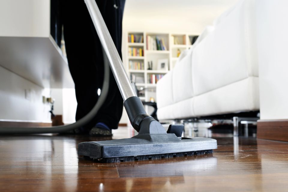A person vacuuming a wood floor