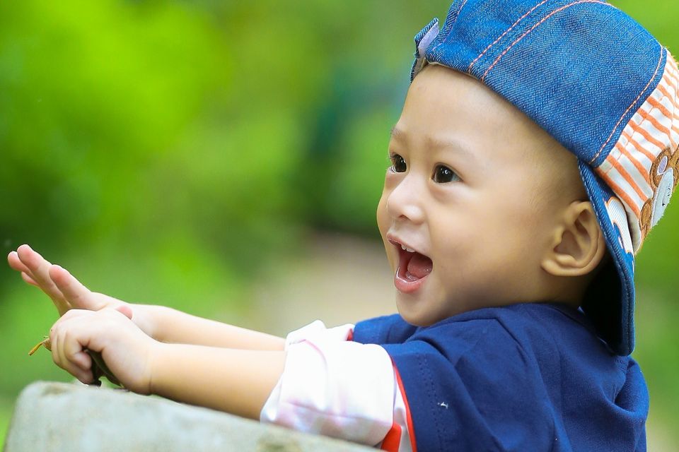 Smiling toddler in a denim cap pointing outdoors during preschool outdoor play in Palmdale CA
