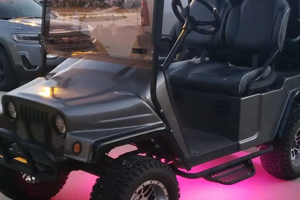 Custom golf cart with pink undercarriage lights parked in a driveway in Metairie, LA