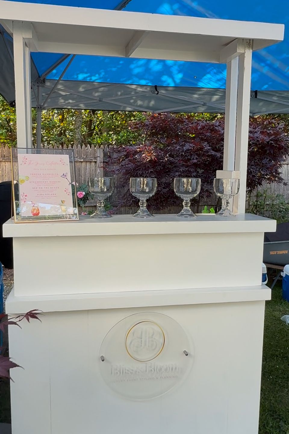 White mobile bar cart with cocktail menu and glassware set up for bartending service in the Hamptons NY