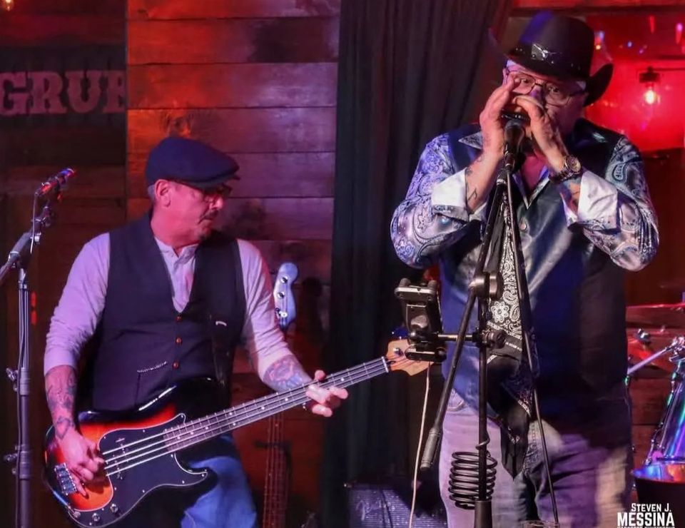 Roadside bassist and harmonica player performing together during a live blues set at a Long Island pub