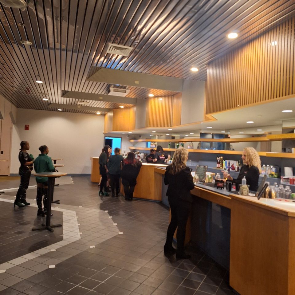 Bartenders serving drinks at a large indoor bar setup during a formal event