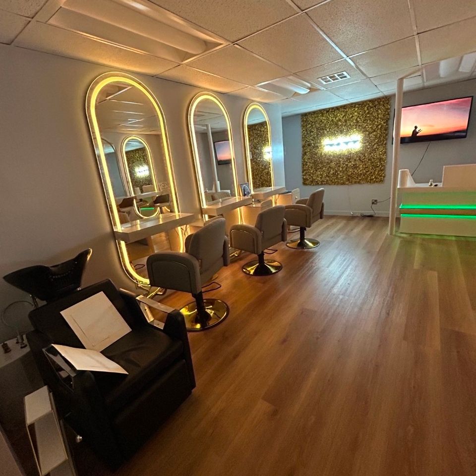 Salon interior with lighted arch mirrors styling chairs and wash station at an African hair braiding shop in Los Angeles