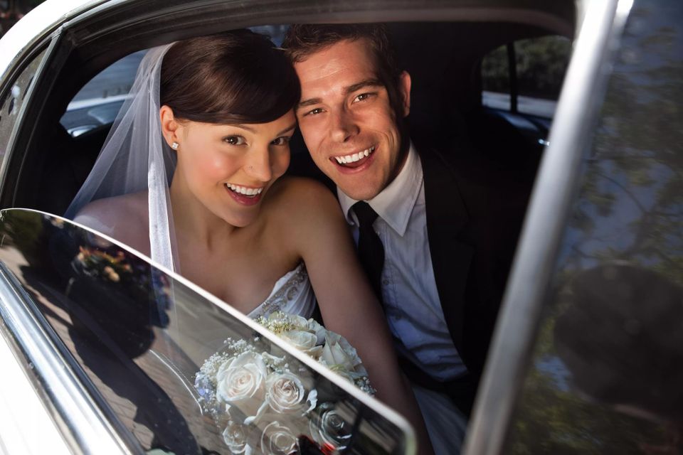 Newly married couple in the back of their limo smiling out the window