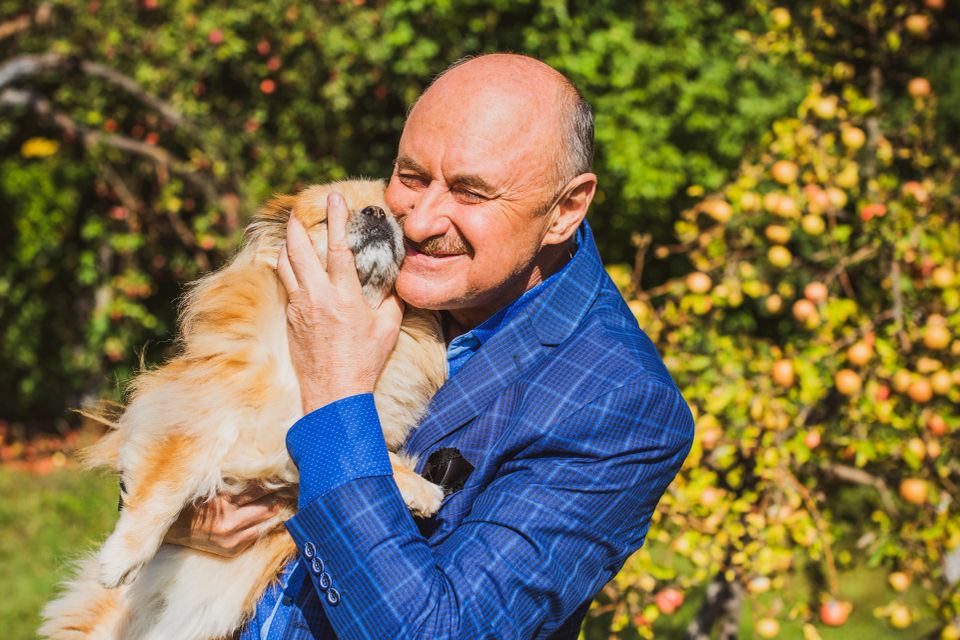 Smiling senior man holding his dog outdoors enjoying pet companion care on Long Island NY