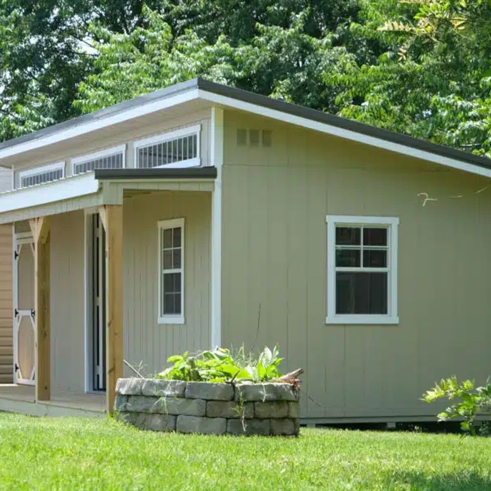 Sage green studio shed with covered porch and clerestory windows in a Knoxville TN backyard