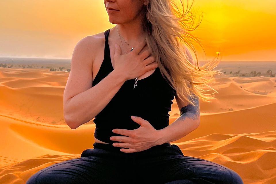 Meg Donnelly of Blackbird Breathwork in position on a sandy knoll for healing breathwork