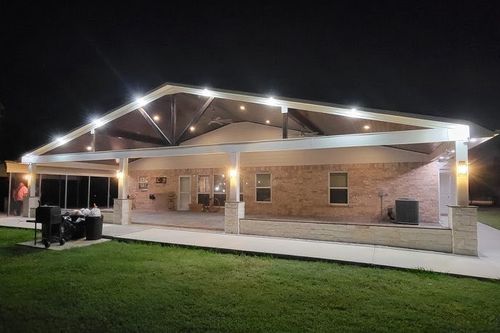 Expansive patio cover with stone bases and metal truss in Tomball, TX