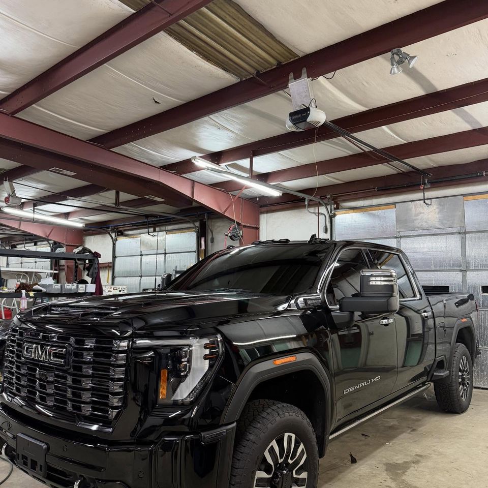 Black GMC Sierra Denali HD crew cab with dark window tint in a Moyock NC tint shop bay