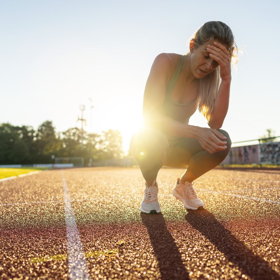Distressed female athlete resting on a running track