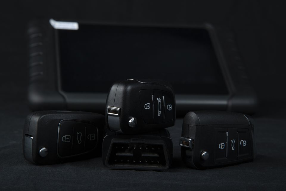 Car keys with car-key-programming devices and tools, exemplifying the skillset of a proficient car key locksmith