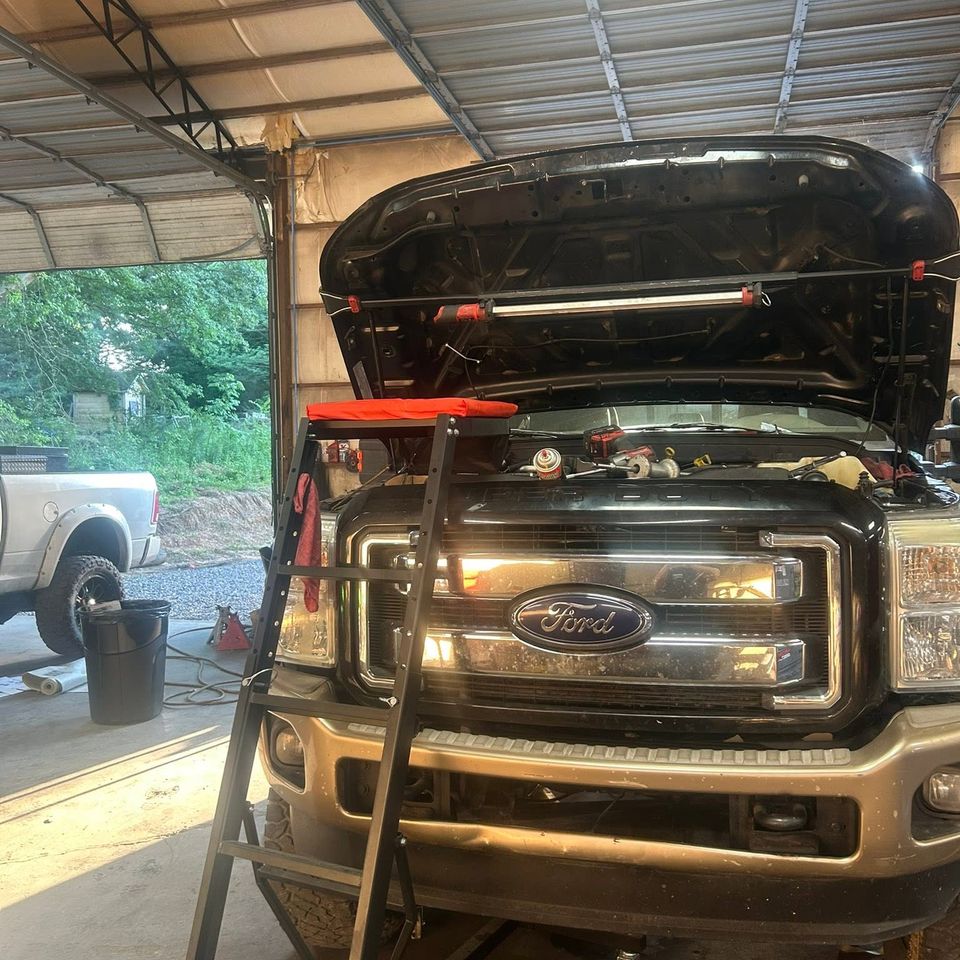 Black Ford Super Duty truck with hood open inside diesel repair service bay in Arab Alabama
