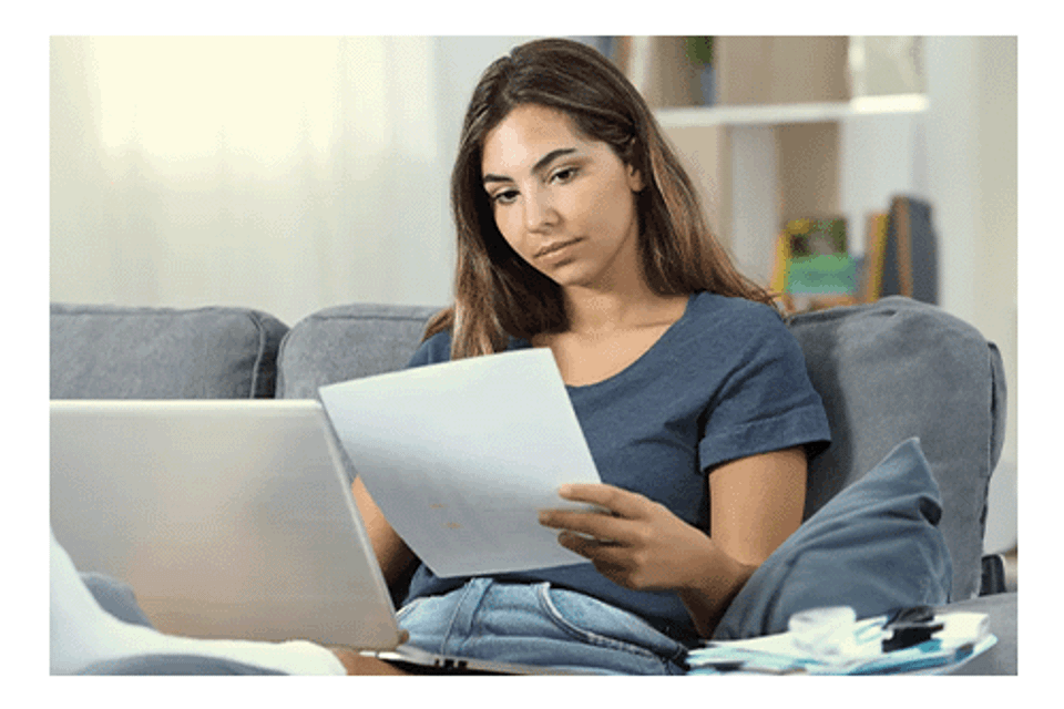 Girl reviewing paper with laptop