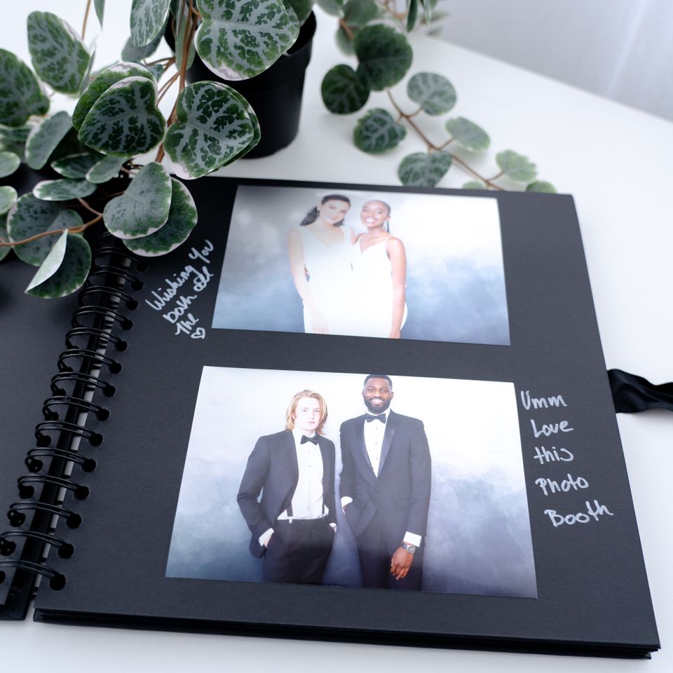 Open photo guestbook with printed photo booth pictures and handwritten notes.