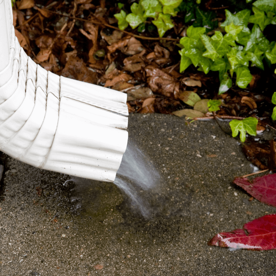Water flowing from the downspout of a cleaned gutter.