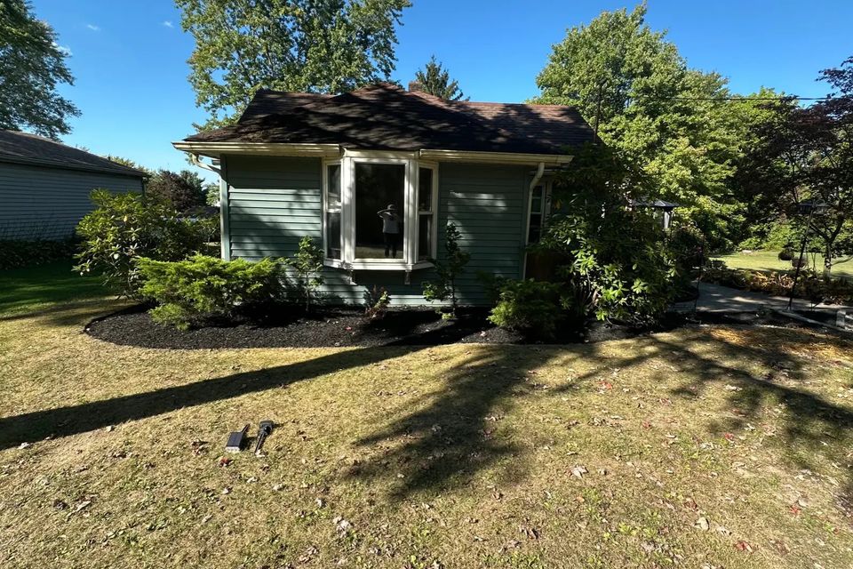 Front view of a residential home featuring professionally landscaped flower beds, fresh mulch, trimmed shrubs, and a maintained lawn by R.E.P. Companies.
