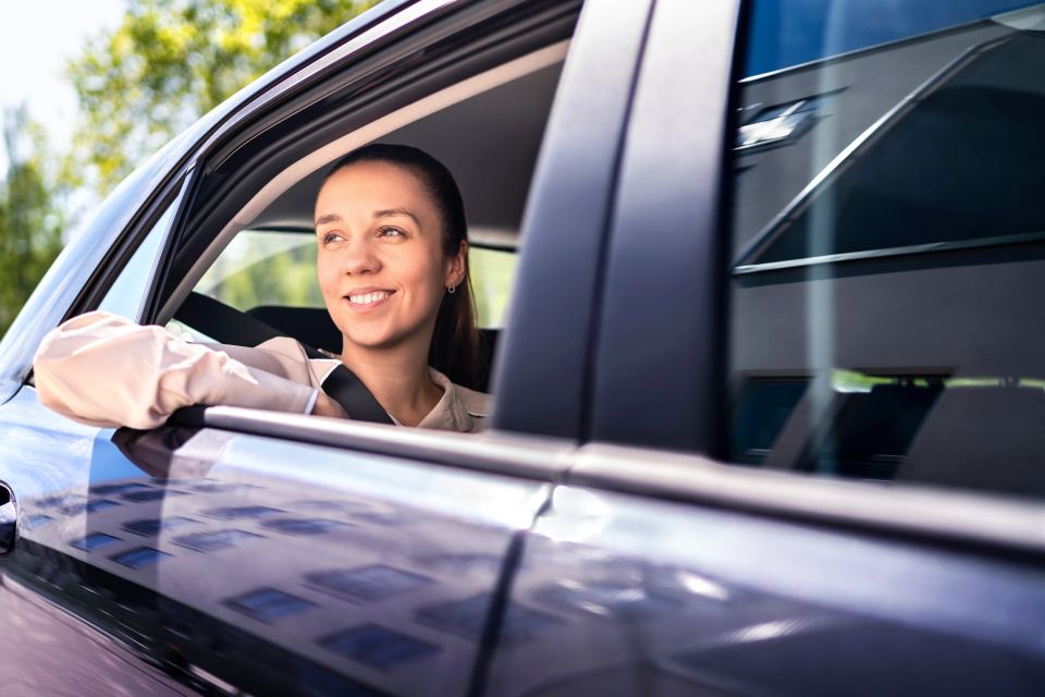 Woman in car as passenger on the backseat. Smiling female customer in taxi cab looking out the window