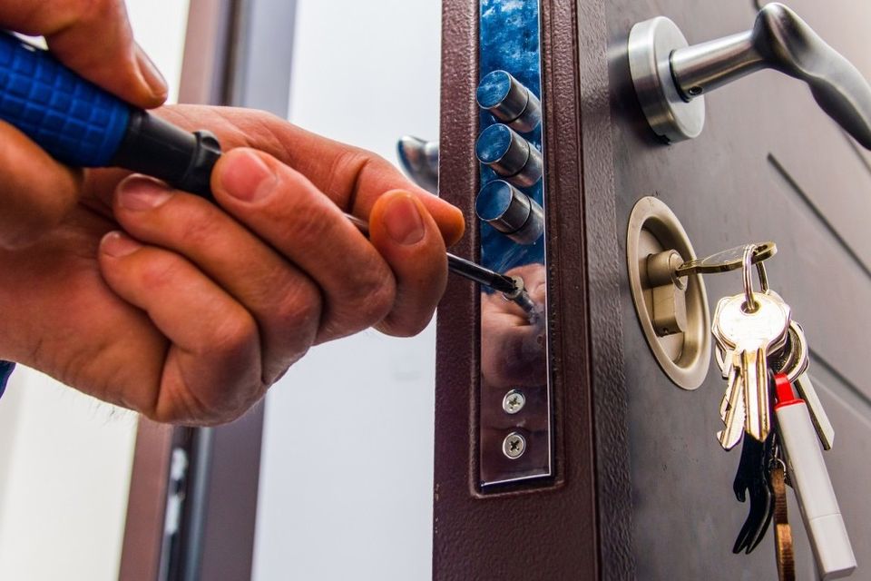 Residential locksmith using a screwdriver to install a new security lock.