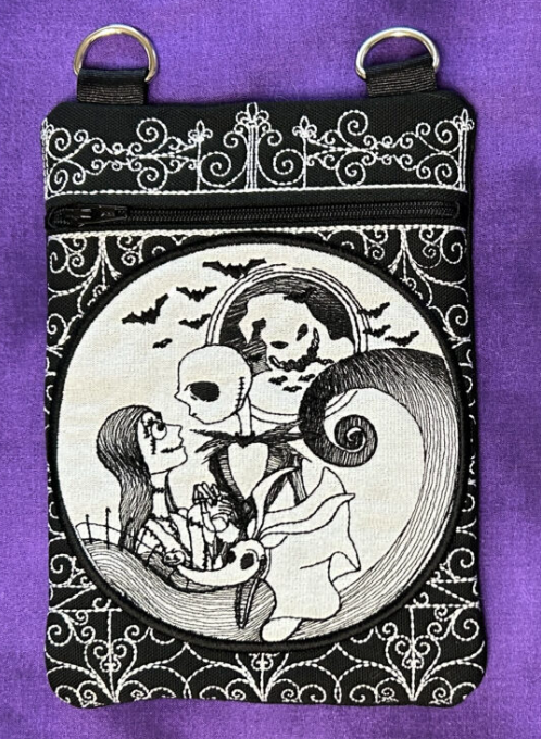 Black embroidered zipper pouch with gothic character artwork, bats, and ornate decorative stitching.