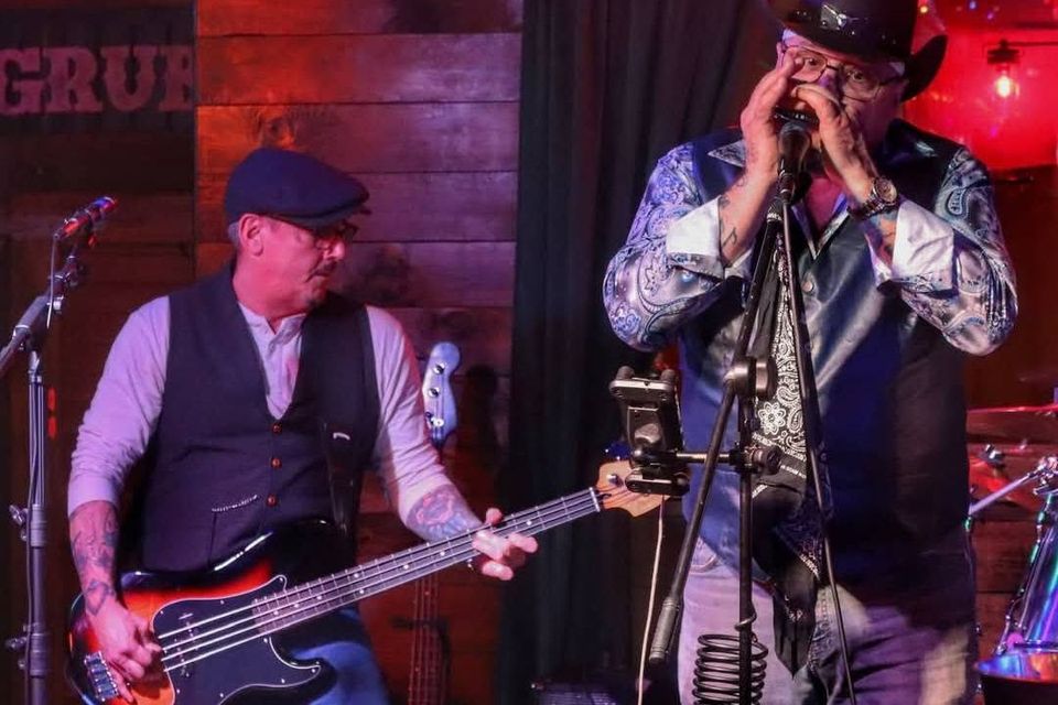 Roadside bassist and harmonica player performing together during a live blues set at a Long Island pub