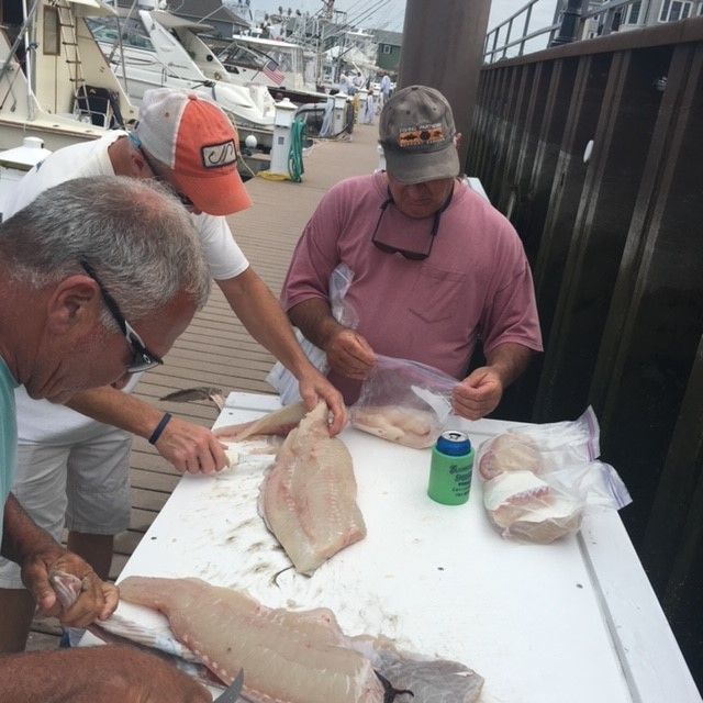 3 men preparing packaging fish caught on charter for renters to take home
