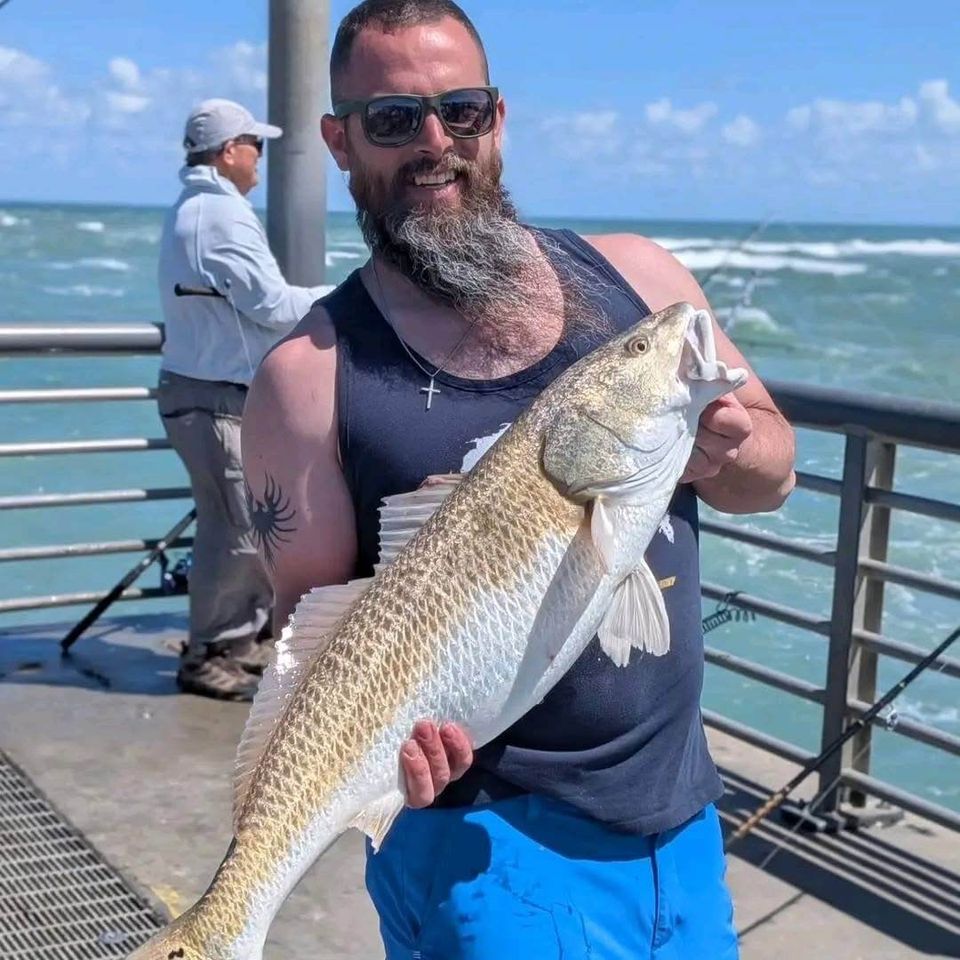 Angler holding a large redfish on a pier