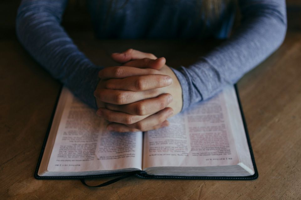 Congregation member with hands on open bible at Open Bible Church