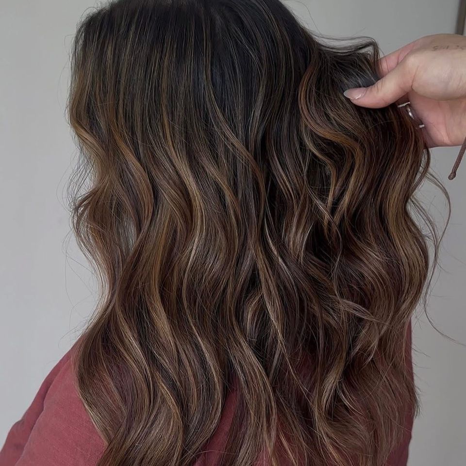 Long wavy dark brown hair with warm caramel balayage highlights after color service in Columbiana AL