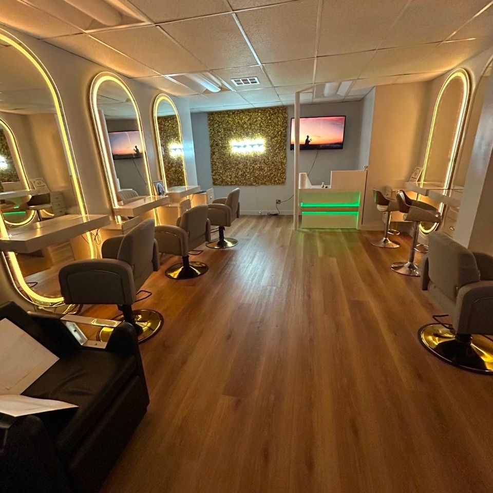 Wide view of hair braiding stations with backlit mirrors and reception desk inside the Los Angeles salon