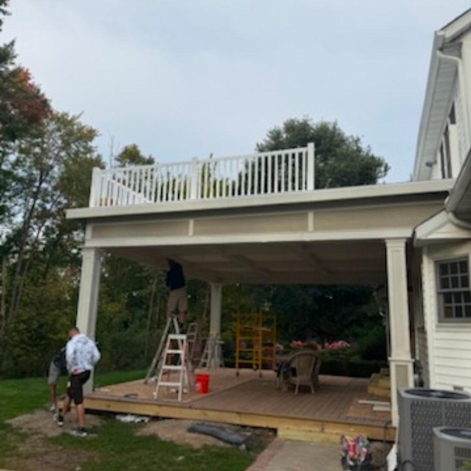 Crew finishing a covered porch with a rooftop deck and white vinyl railing at a Cleveland East Side home