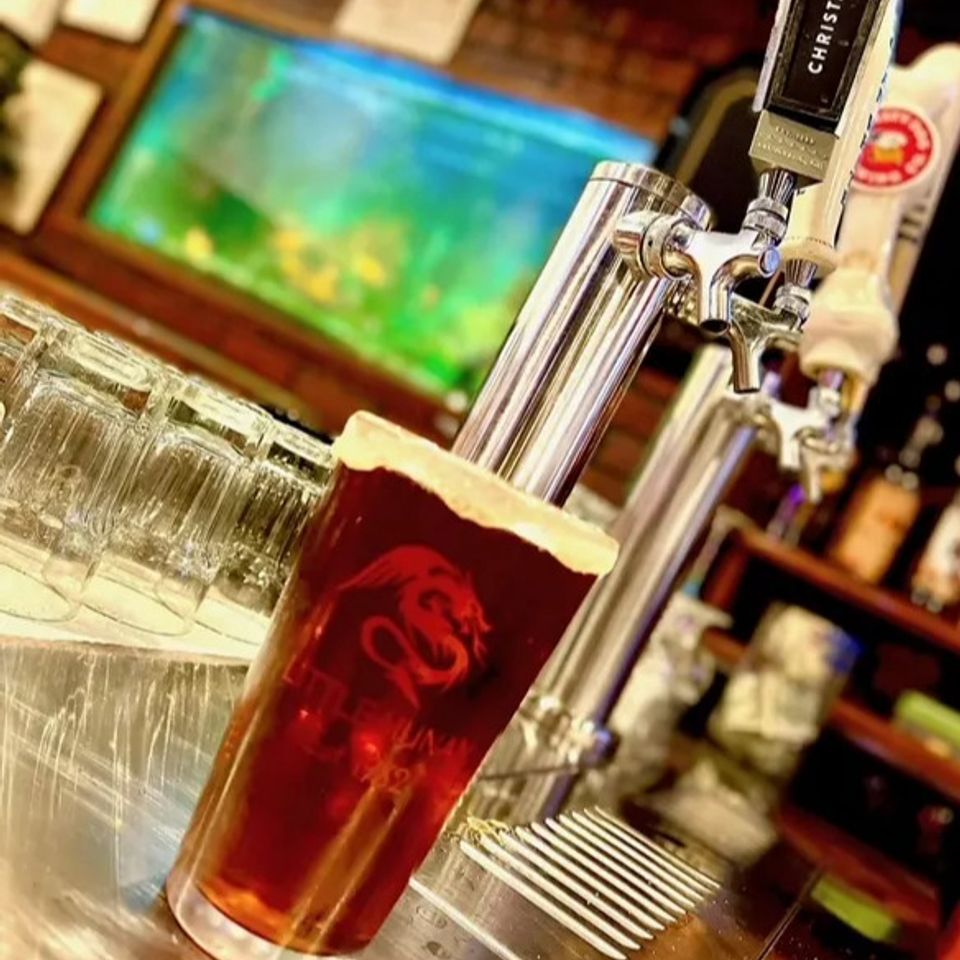 Freshly poured beer in a pint glass at the Little Hunan bar with beer taps in the background.