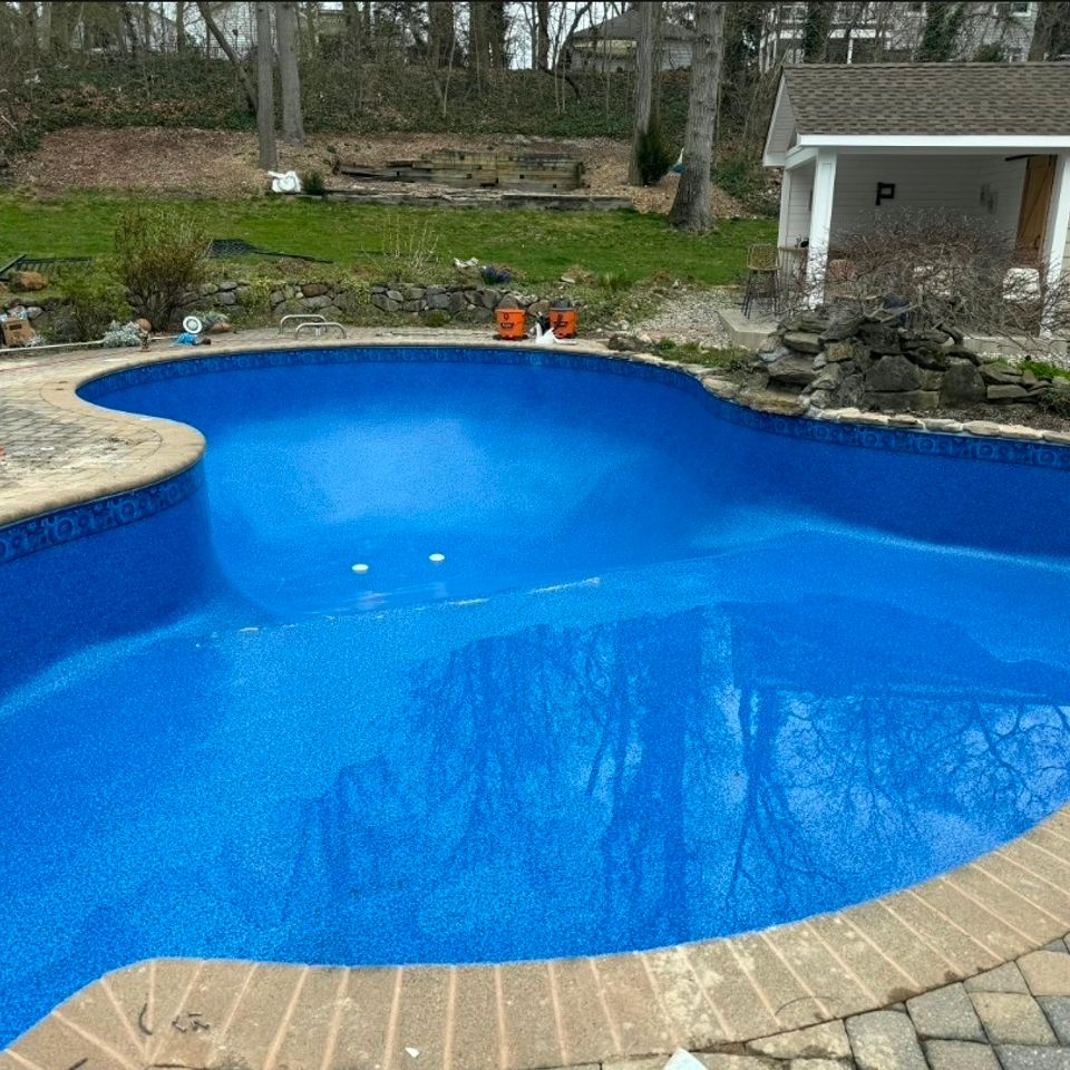 Freeform inground pool with fresh blue liner and paver coping filled after a liner replacement in Long Island NY