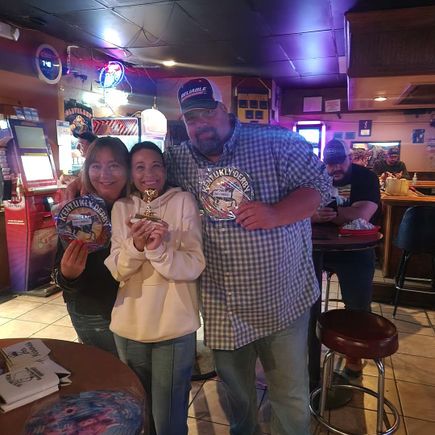 Three guests displaying a trophy and Kentucky Derby memorabilia at JR's Kentucky Derby event.
