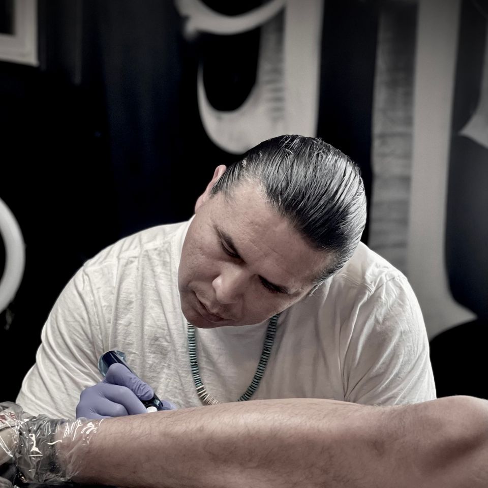 Image of Adrian at work laying down a tattoo on a man's right calf